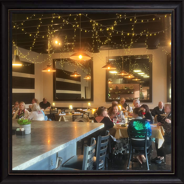 People dining in Cafe Catron Santa Fe NM, surrounded by string lights and modern decor.