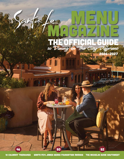 Three people dine outdoors by adobe at Cafe Catron, featured on Santa Fe Menu Magazine 2026–2027.