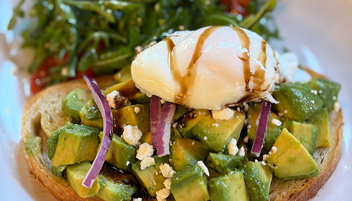 Avocado toast from the Cafe Catron menu with poached egg, feta, red onion, and balsamic glaze.